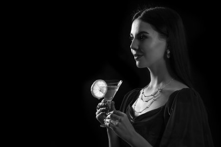 Beautiful young woman with martini on dark backgroundの写真素材