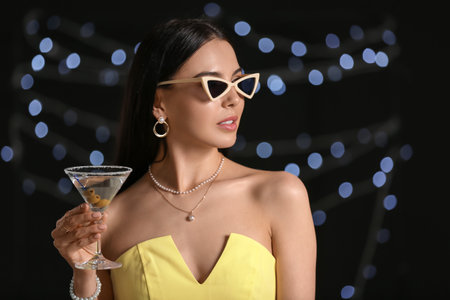 Beautiful young woman with martini on dark backgroundの写真素材