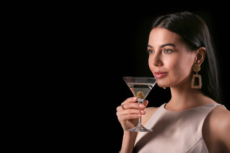 Beautiful young woman with martini on dark backgroundの写真素材