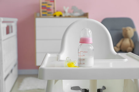 Bottle of milk for baby on high chair in roomの写真素材