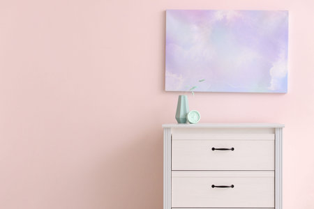 Modern chest of drawers with decor near color wall in room