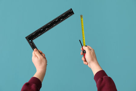 Worker with ruler and measure tape on blue backgroundの写真素材