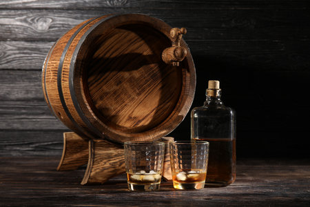 Oak barrel with bottle and glasses of cold whiskey on dark wooden backgroundの写真素材