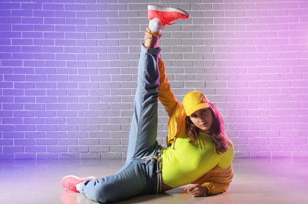 Beautiful female hip-hop dancer against brick wallの写真素材