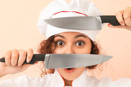 Surprised African-American chef with knives on color backgroundの写真素材