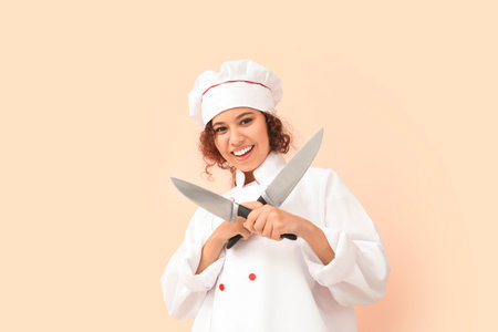 Female African-American chef with knives on color backgroundの写真素材