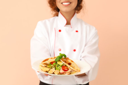 Female African-American chef with tasty dish on color backgroundの写真素材