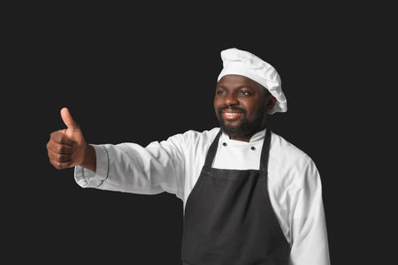 Male African-American chef showing thumb-up on dark backgroundの写真素材