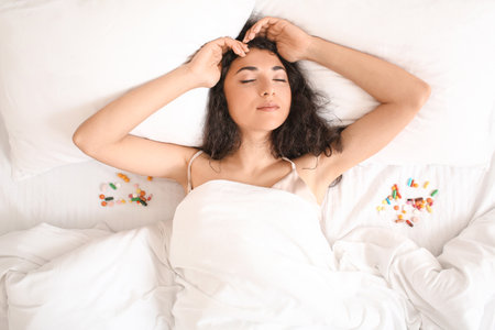 Young woman with sleeping pills in bedの写真素材