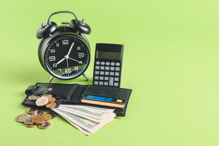 Alarm clock with calculator and money on color backgroundの写真素材