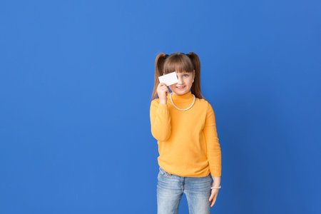 Little girl with business card on color backgroundの写真素材