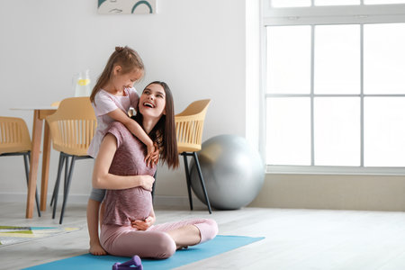 Young pregnant woman and her little daughter practicing yoga at homeの写真素材
