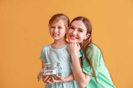 Little girl and her mother with savings for education on color backgroundの写真素材