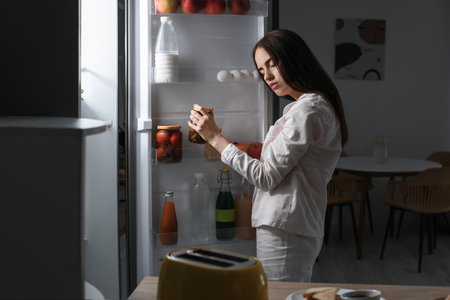 Female sleepwalker near fridge at nightの写真素材