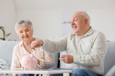 Senior couple with piggy bank at homeの写真素材