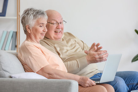 Senior couple with laptop at homeの写真素材