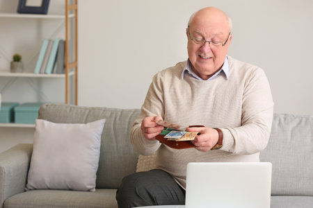 senior man counting money at homeの写真素材