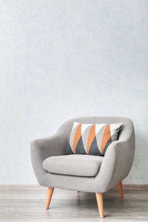 Armchair and soft cushion near light wall in roomの写真素材