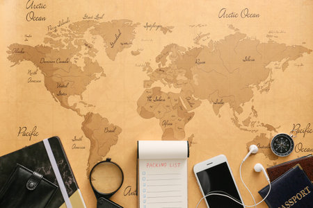 Notebook with check-list of things to pack for travel on world map
