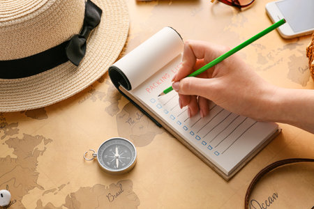 Woman making check-list of things to pack for travelの写真素材