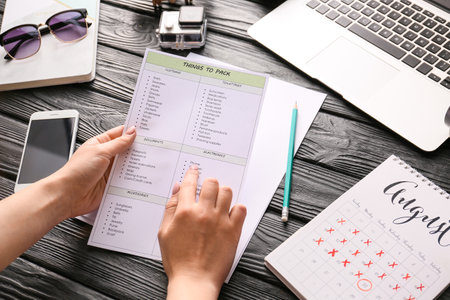 Woman making check-list of things to pack for travelの写真素材