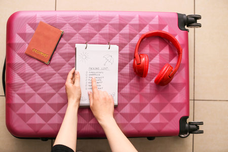 Woman making check-list of things to pack for travel