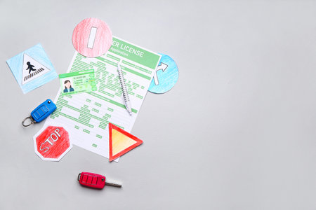 Driving license with application form, car keys and road signs on gray backgroundの写真素材