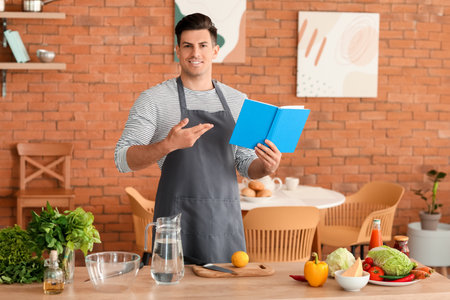 Happy man with recipe book in kitchenの写真素材