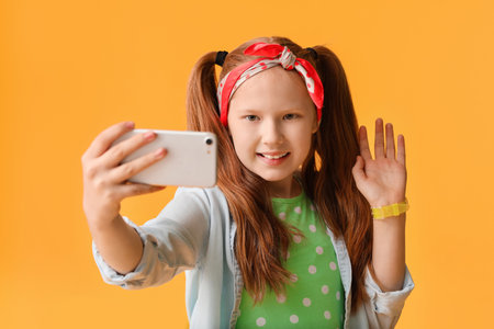 Cute redhead girl taking selfie on color backgroundの写真素材