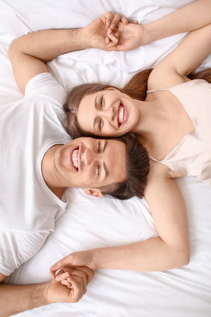 Morning of happy young couple lying in bedの写真素材