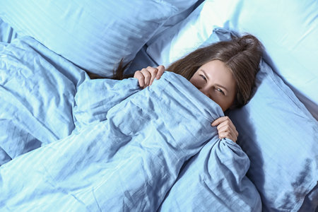 Beautiful young woman in bed at nightの写真素材