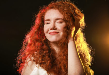 Portrait of beautiful redhead woman on dark background