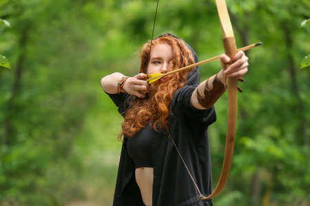 Sporty young woman practicing archery outdoorsの写真素材