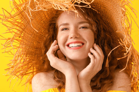 Portrait of beautiful redhead woman in straw hat on color backgroundの写真素材