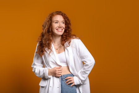 Portrait of beautiful redhead woman on color backgroundの写真素材