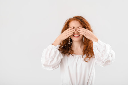 Portrait of beautiful redhead woman on light backgroundの写真素材