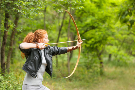 Sporty young woman practicing archery outdoorsの写真素材