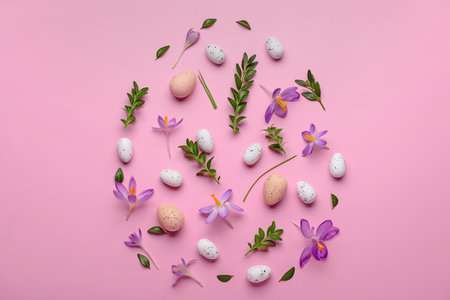 Creative composition with Easter eggs, beautiful crocus flowers and plant leaves on pink backgroundの写真素材