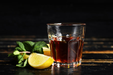 Glass of rum with lime and mint leaves on dark wooden backgroundの写真素材