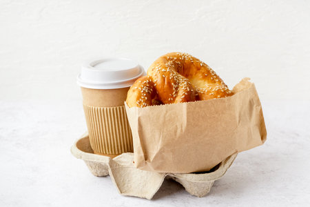 Tasty pretzel and cup of coffee on light backgroundの写真素材