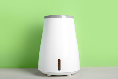 Modern humidifier on table near green wallの写真素材