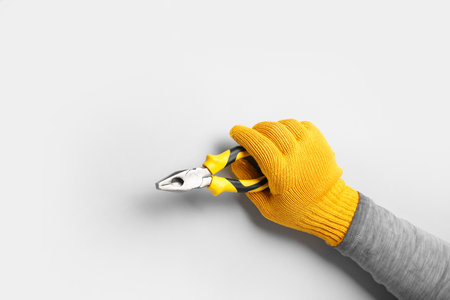 Male hand in gloves holding pliers on white backgroundの写真素材