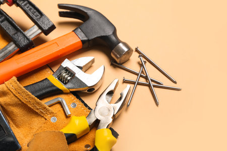Pliers in belt with tools on beige backgroundの写真素材