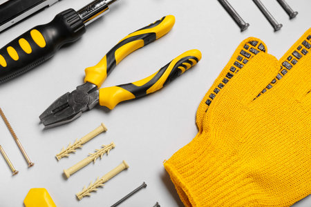 Pliers, gloves and screws on gray background