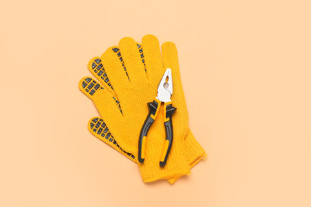 Pliers and gloves on beige backgroundの写真素材