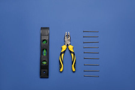 Pliers, level and nails on blue backgroundの写真素材