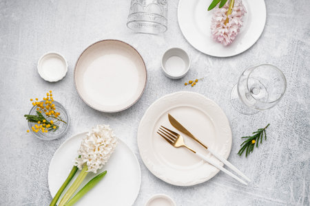Composition with clean dishes, cutlery and beautiful flowers on gray grunge background