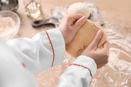 Female chef preparing dough for pasta at table in kitchen, closeupの写真素材