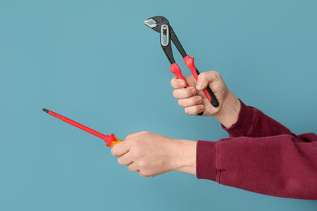 Worker with pliers and screwdriver on blue backgroundの写真素材