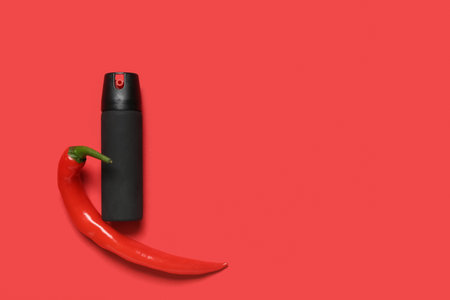 Spray with chili pepper on red backgroundの写真素材